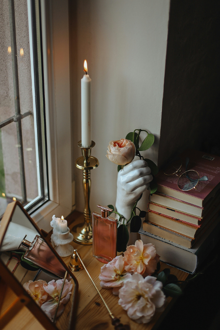 Lit candle on table with books and flowers